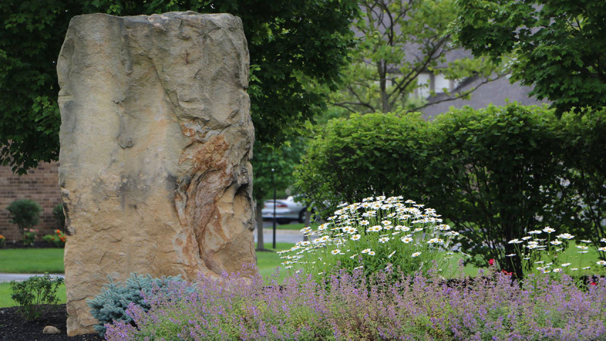 Scenic photo of flowers and a standing stone